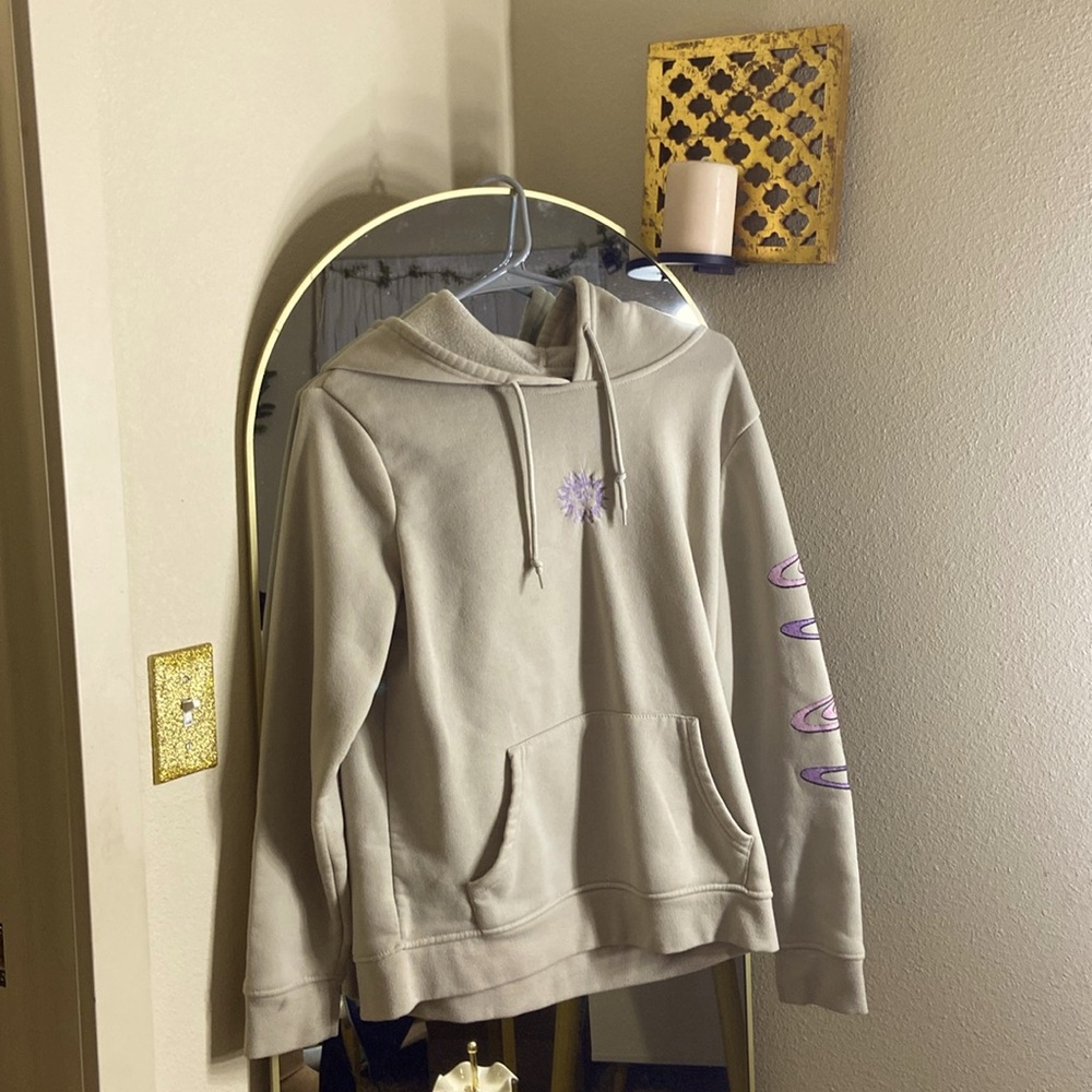 A gray hoodie with an embroidered sun on front and design on back.